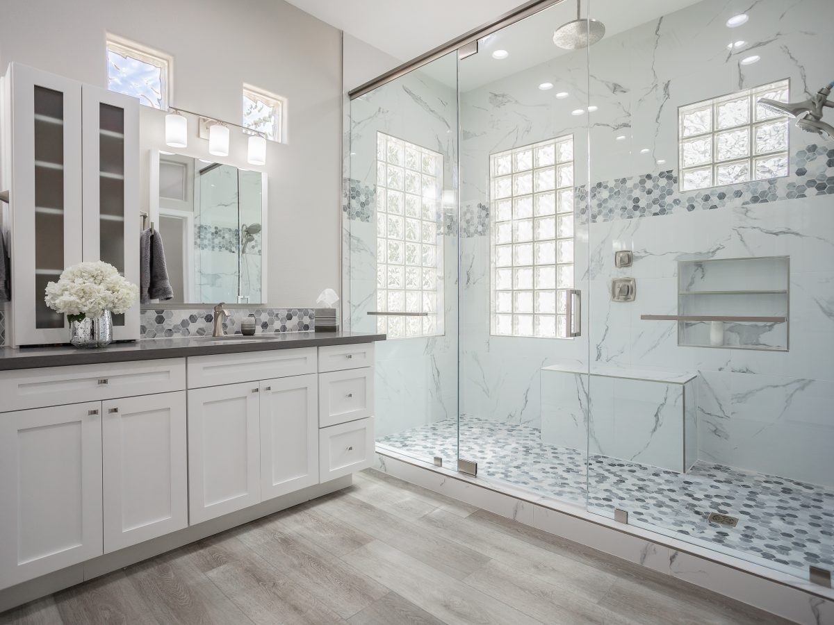 Primary bathroom with marble-look porcelain shower, white shaker vanity, and greige quartz countertops, Reveal Interior Design Las Vegas