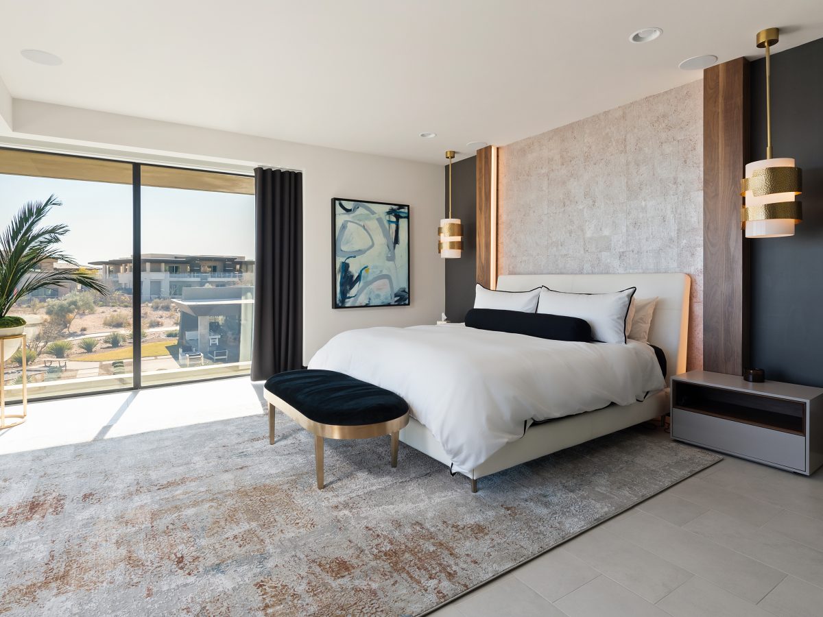 Primary bedroom with floor-to-ceiling walnut headboard wall, leather-wrapped king bed, and Ridges views, Reveal Interior Design Las Vegas