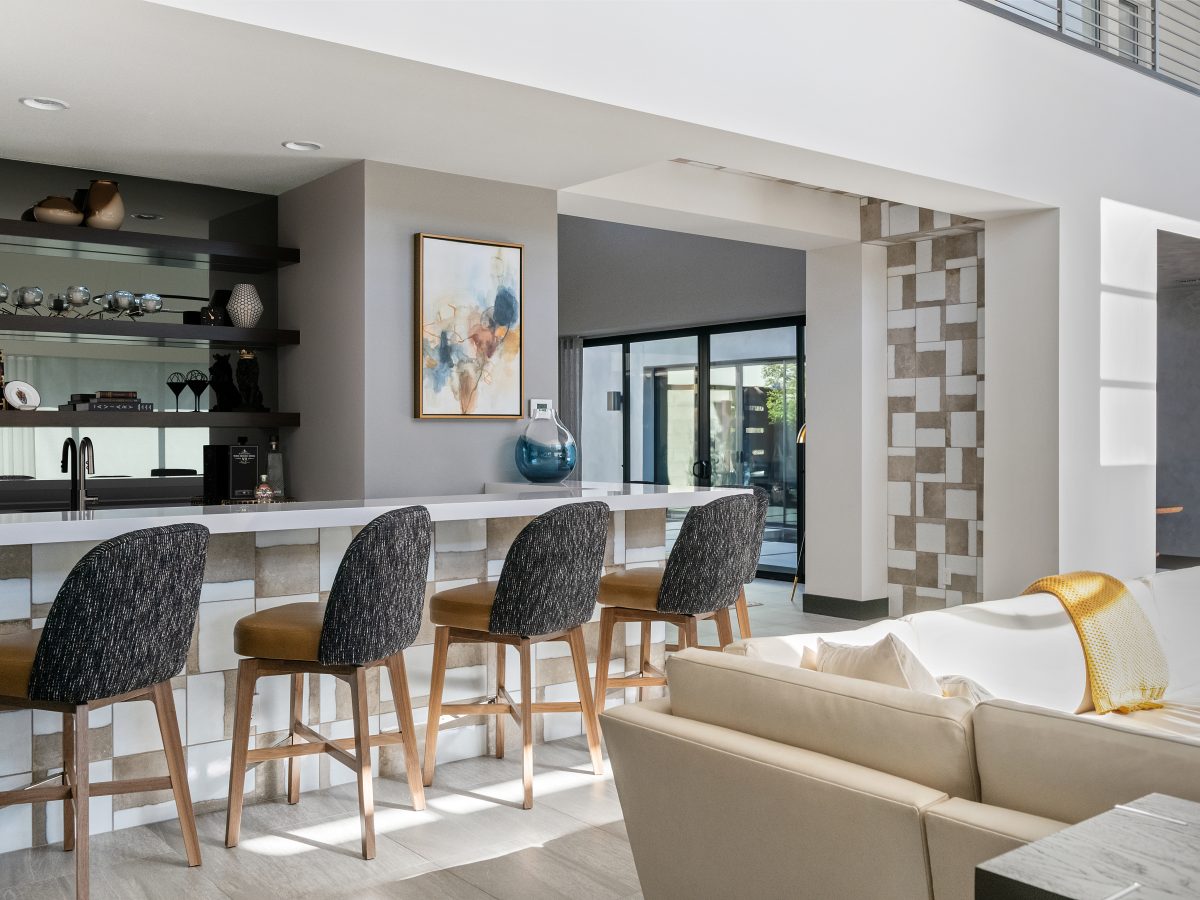 Mid-century modern bar with white quartz countertop, ceramic tile front, and custom cognac leather barstools, Reveal Interior Design Las Vegas