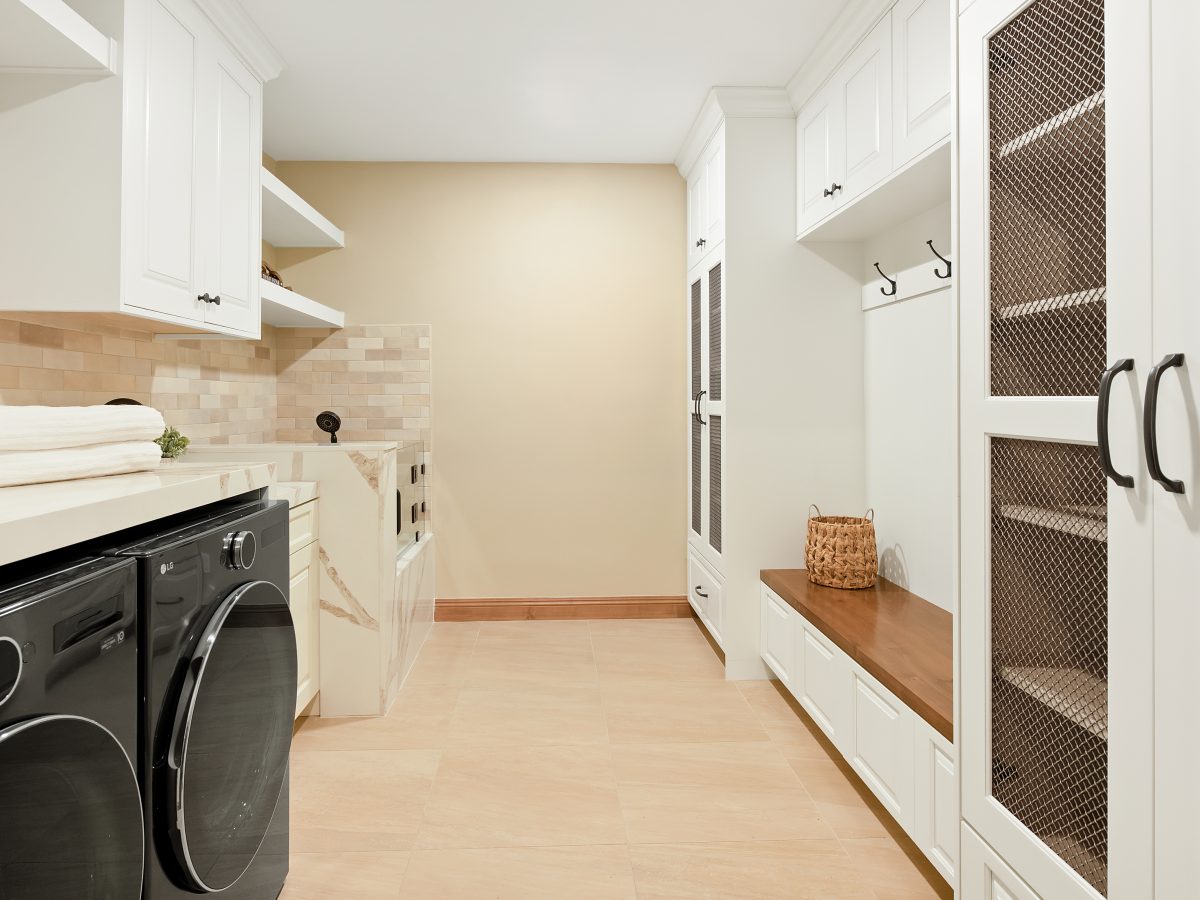 Modern Spanish laundry and mudroom with cream cabinetry, bronze mesh doors, and quartz countertops, Reveal Interior Design Las Vegas