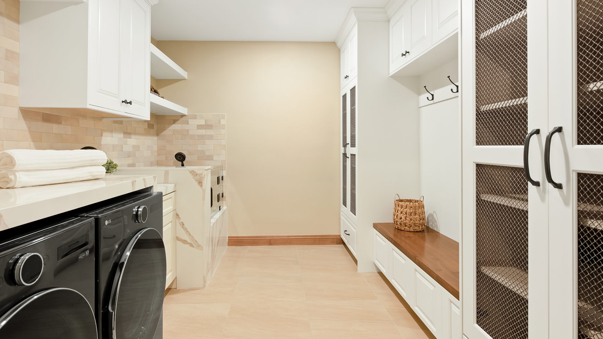Modern Spanish laundry and mudroom with cream cabinetry, bronze mesh doors, and quartz countertops, Reveal Interior Design Las Vegas