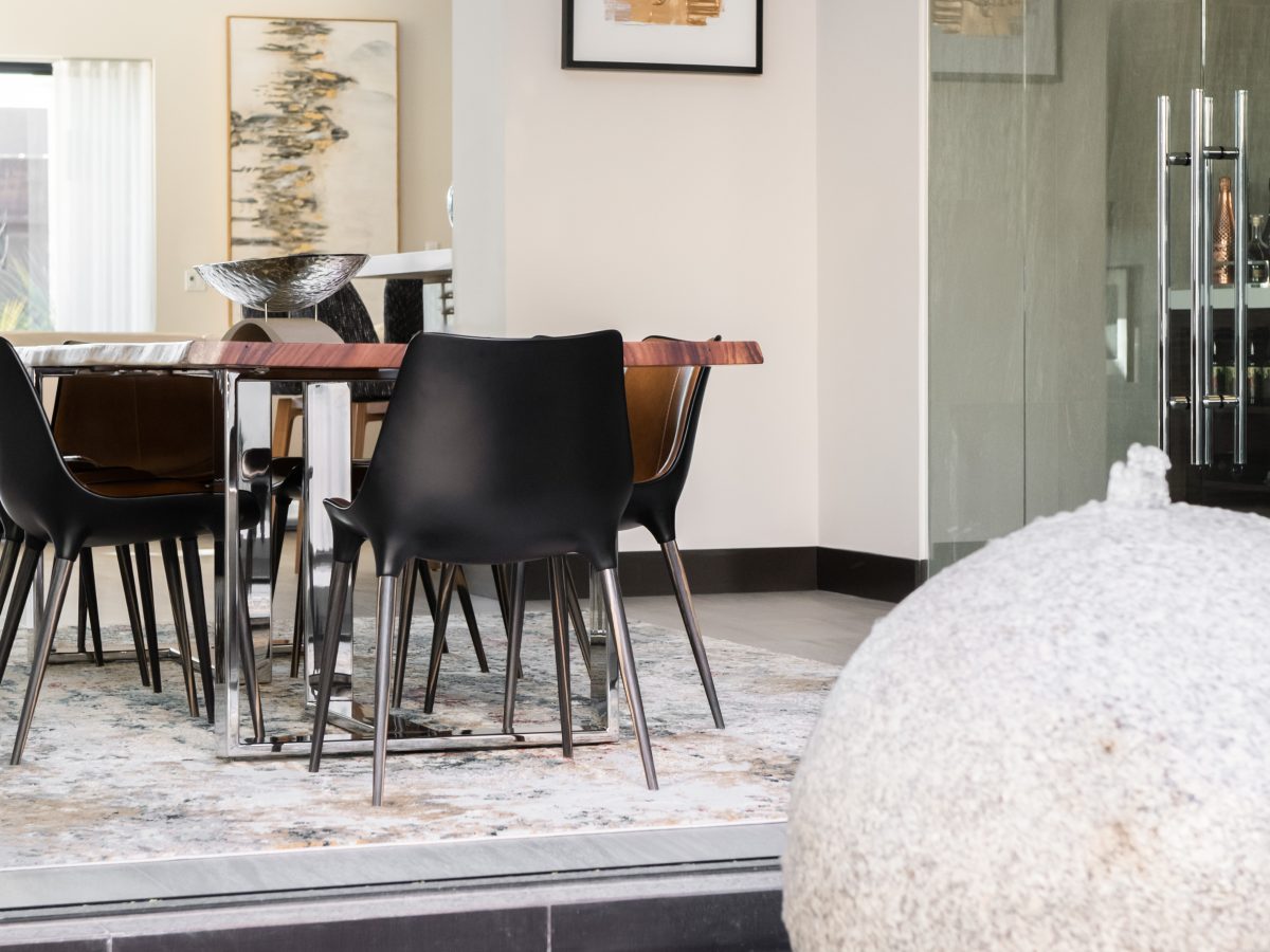 Dining room with custom live-edge wood table, two-tone leather seating, and enclosed wine room, Reveal Interior Design Las Vegas