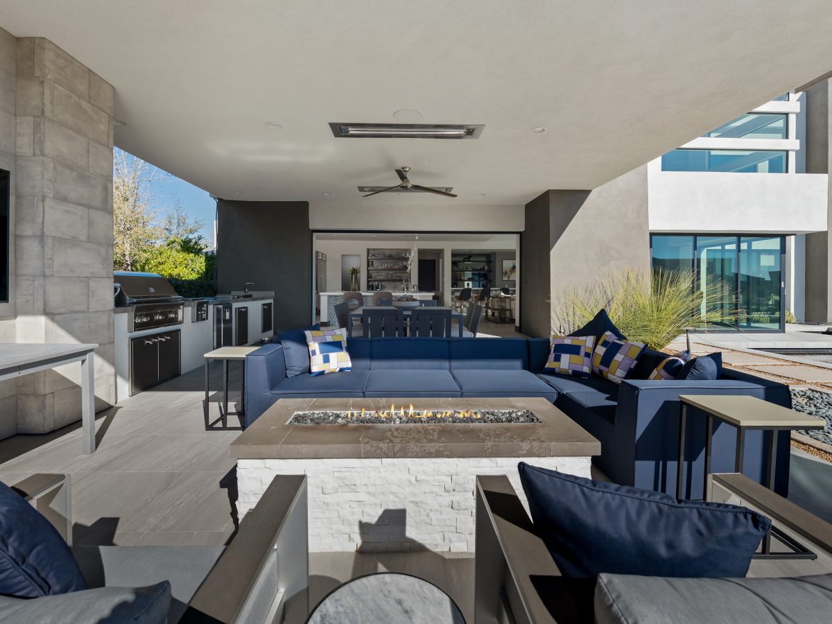 Covered outdoor living space with linear fire table and navy sectional seating, Reveal Interior Design Las Vegas