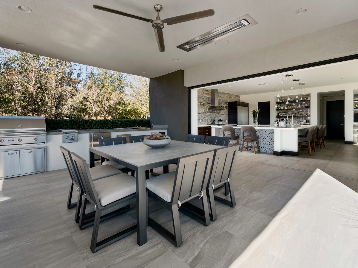Covered outdoor dining and kitchen area with ceiling fan and strip views, Reveal Interior Design Las Vegas