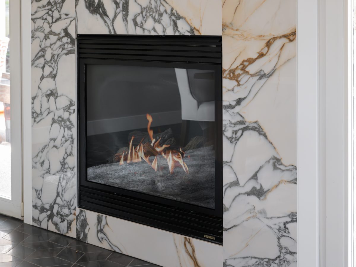 Marble-surround gas fireplace with black frame and hexagonal floor tile, Reveal Interior Design Las Vegas