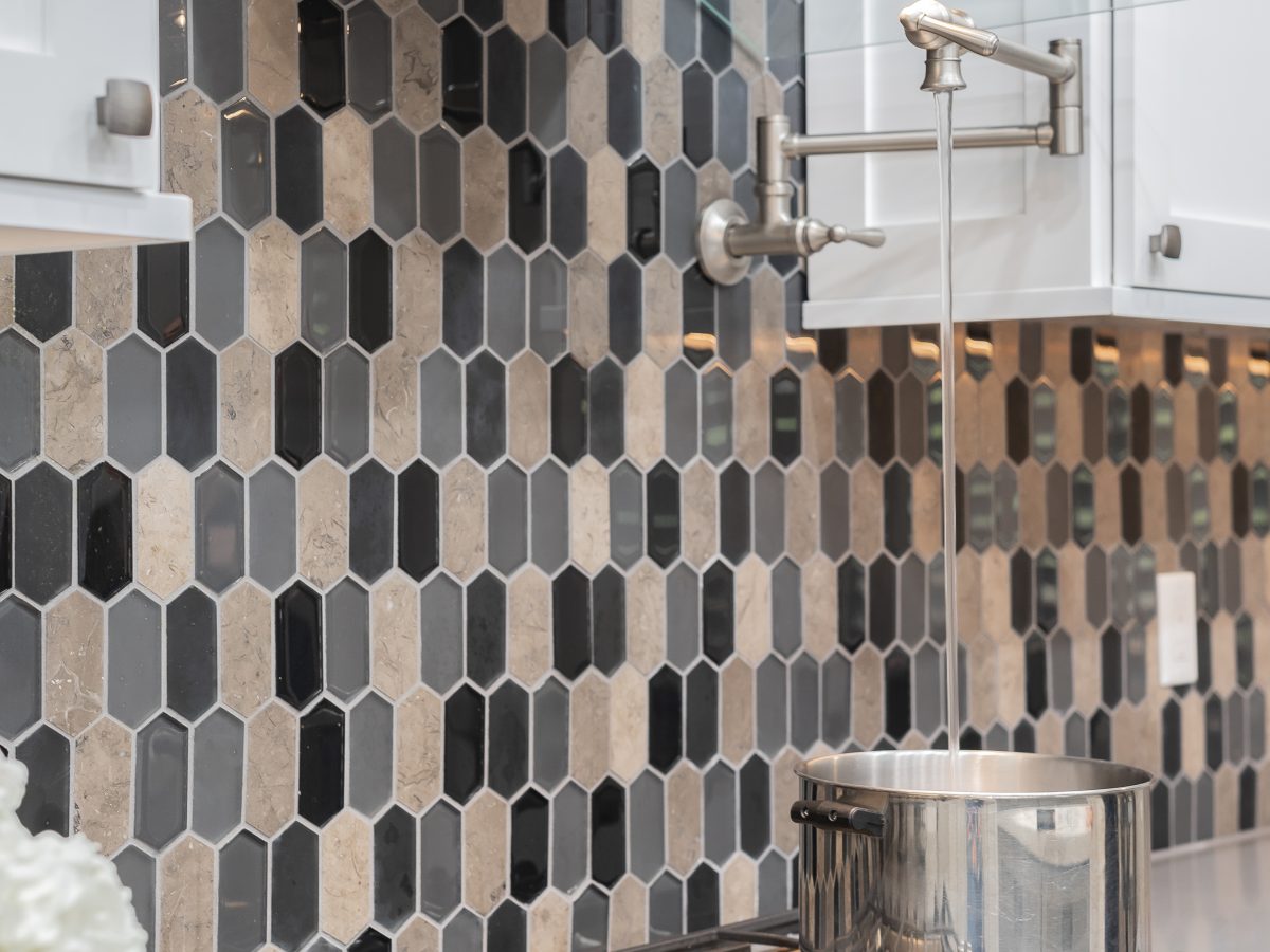 Kitchen cooktop with elongated hex glass and stone mosaic backsplash and pot filler, Reveal Interior Design Las Vegas