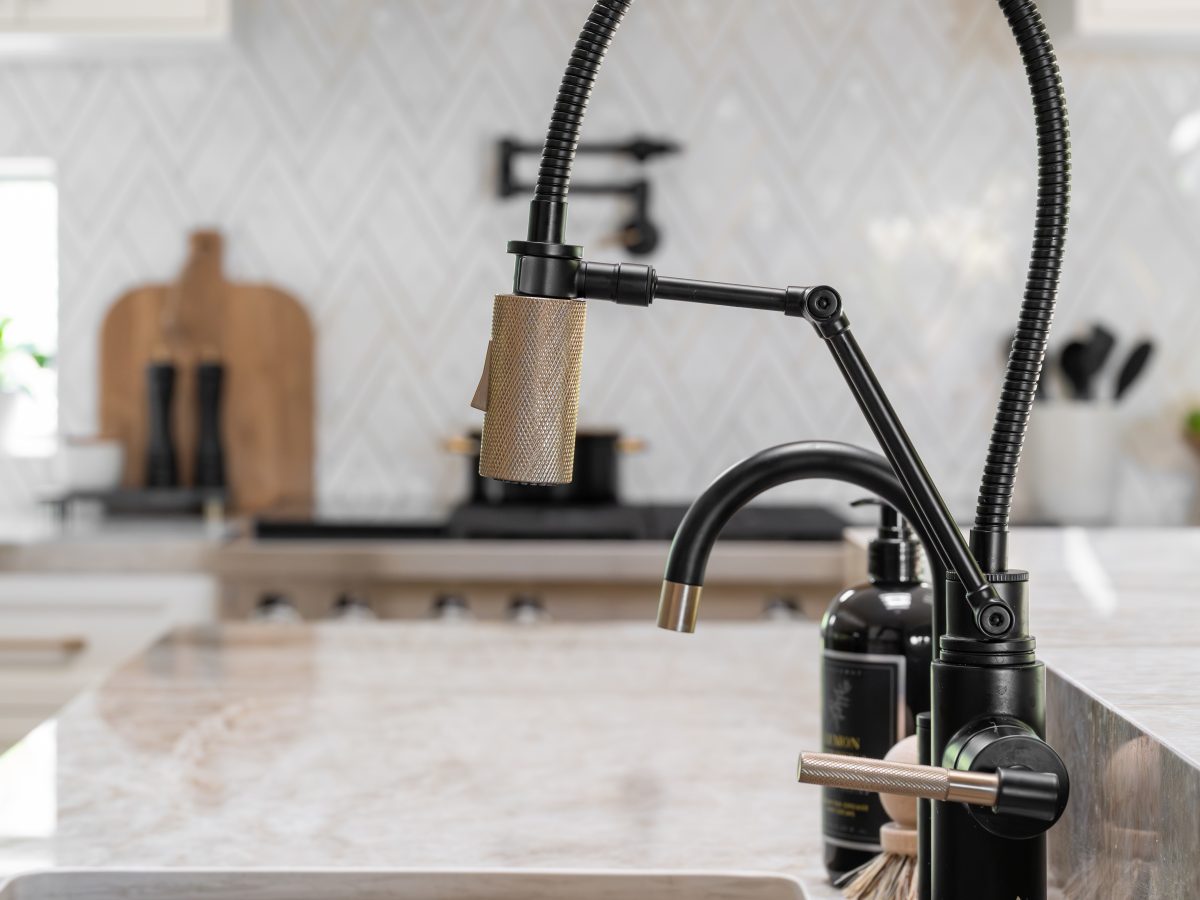 Kitchen sink detail with matte black pull-down faucet and Dekton Taj Mahal countertop, Reveal Interior Design Las Vegas