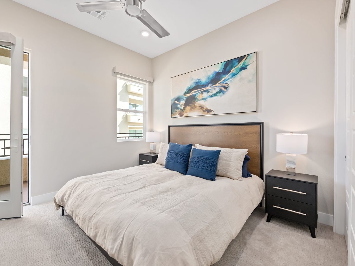 Contemporary guest bedroom with taupe carpet, warm brown headboard, and bold art, Reveal Interior Design Las Vegas