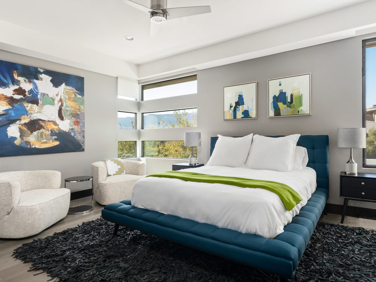 Contemporary secondary bedroom with teal tufted bed frame and bold abstract artwork, Reveal Interior Design Las Vegas