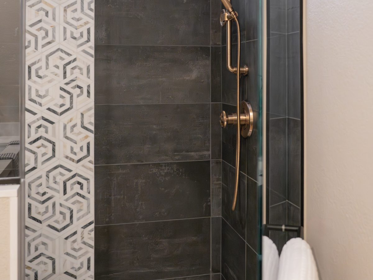 Walk-in shower with geometric mosaic tile and brushed brass fixtures, Reveal Interior Design Las Vegas