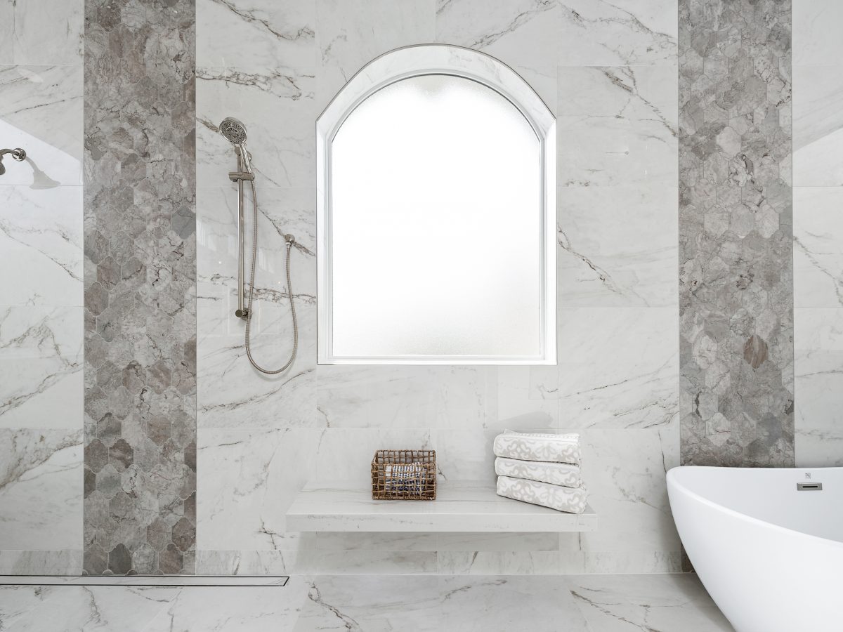 Transitional wet room primary bathroom with marble-look porcelain tile and Taj Mahal quartzite bench, Reveal Interior Design Las Vegas