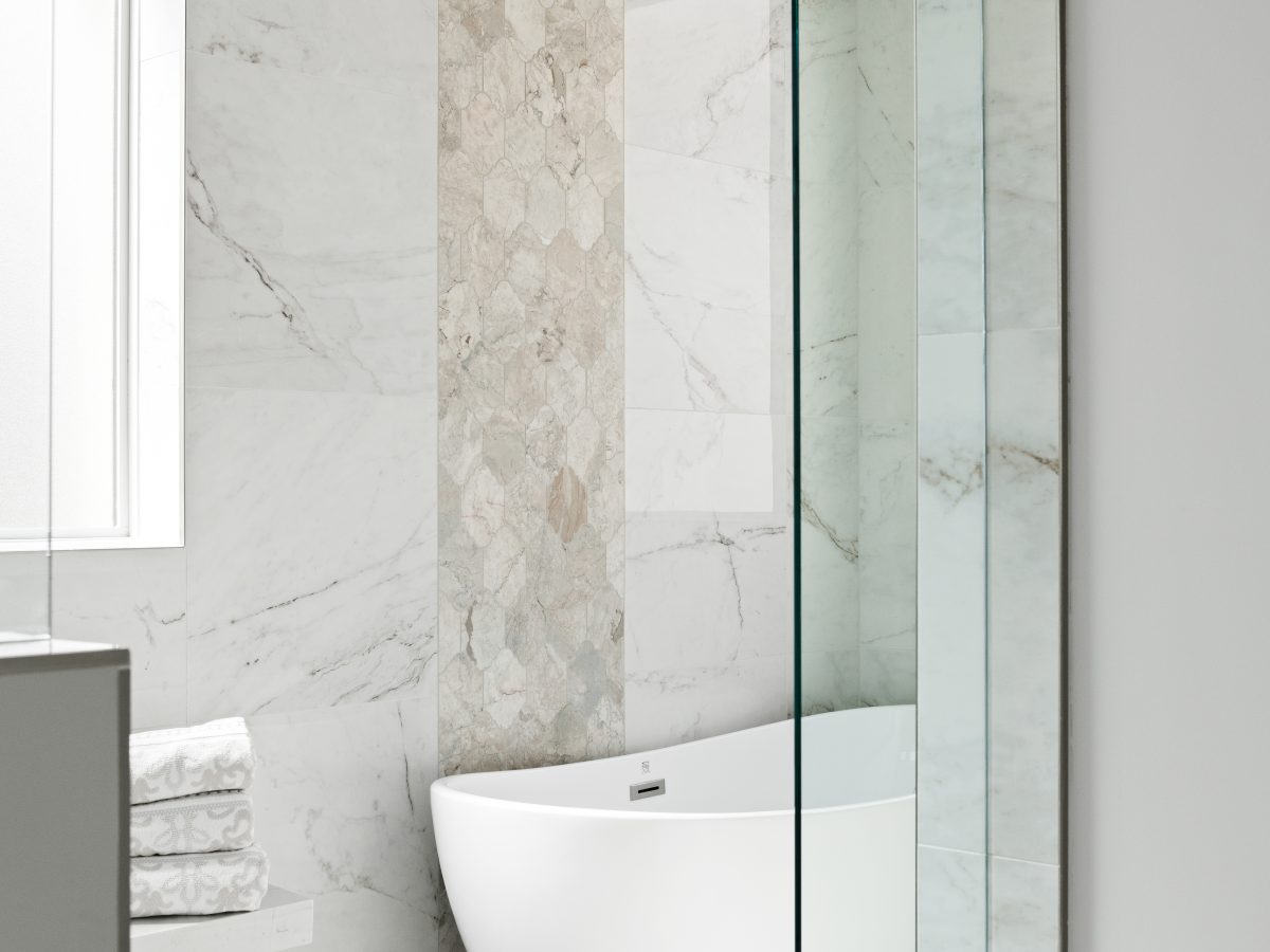 Transitional primary bathroom wet room with freestanding tub, marble-look porcelain tile, and vertical accent band, Reveal Interior Design Las Vegas