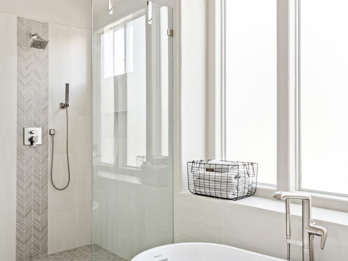 Primary bathroom with freestanding soaking tub, glass walk-in shower, and herringbone porcelain accent tile, Reveal Interior Design Las Vegas