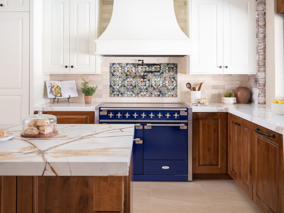 Spanish Modern kitchen with bold blue range, blue-and-gold quartzite island, and cream custom range hood, Reveal Interior Design Las Vegas