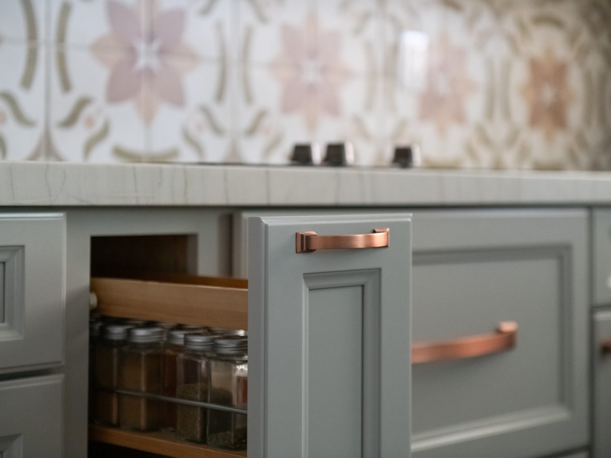 Kitchen pull-out spice drawer with copper hardware and encaustic ceramic tile backsplash, Reveal Interior Design Las Vegas