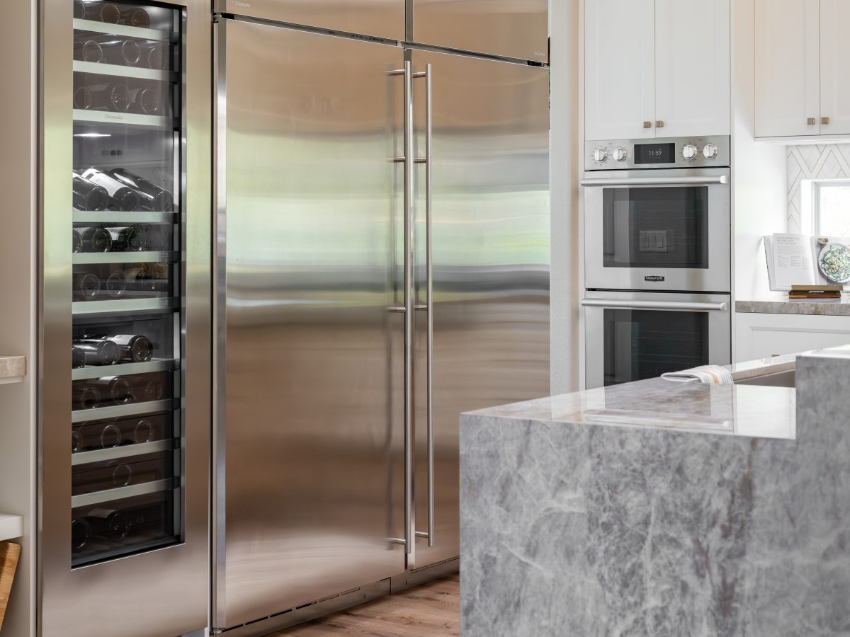 Luxury kitchen with stainless side-by-side refrigerator, wine column, and dekton island, Reveal Interior Design Las Vegas