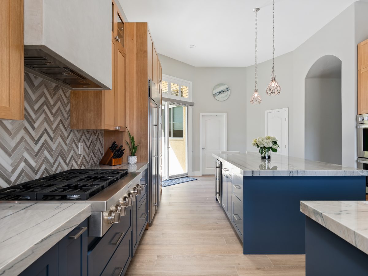 Kitchen with blue base cabinets, warm oak uppers, and quartzite countertops, Reveal Interior Design Las Vegas