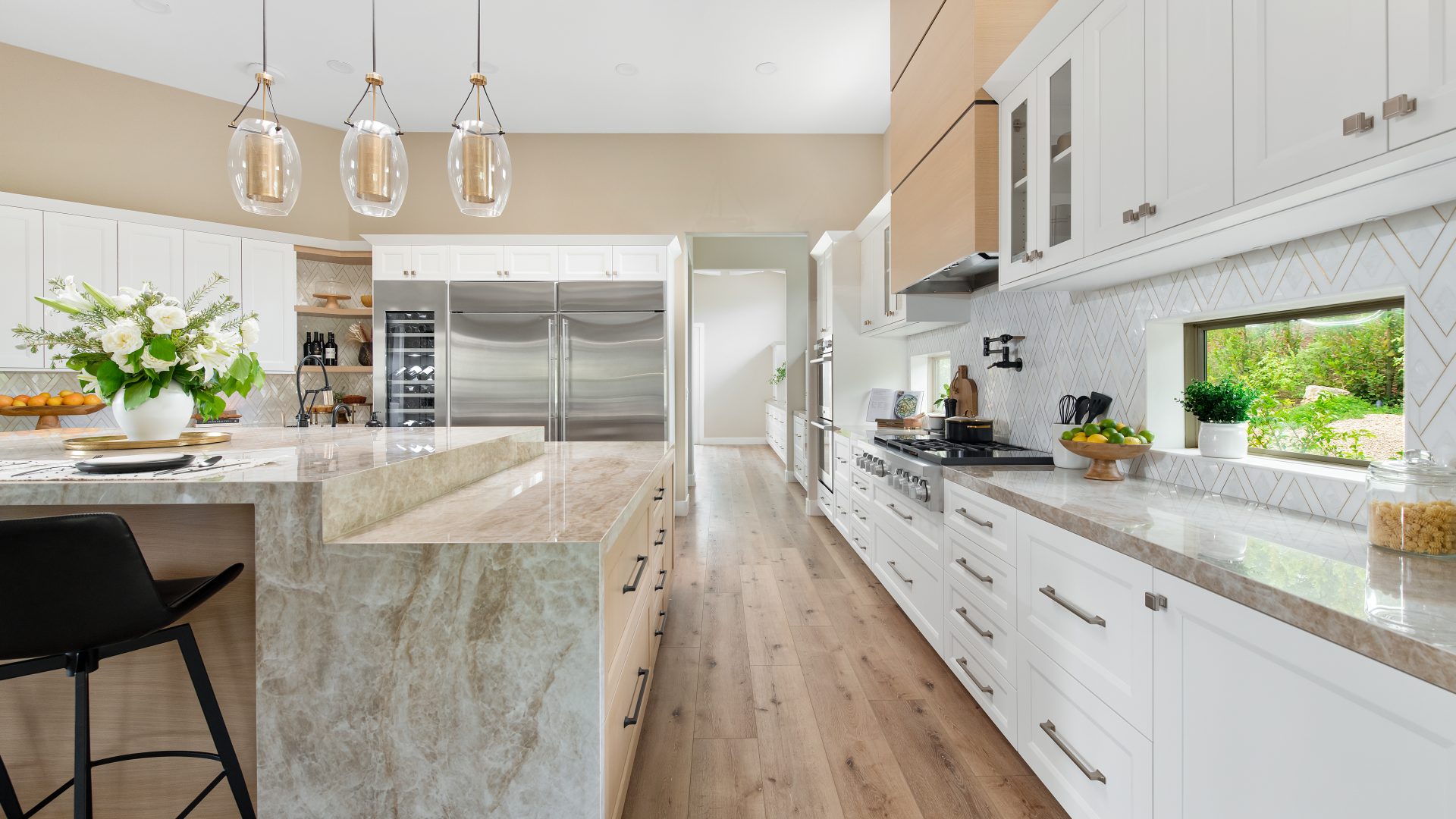 Luxury kitchen with Taj Mahal Dekton island, geometric stone backsplash, and brushed brass accents, Reveal Interior Design Las Vegas