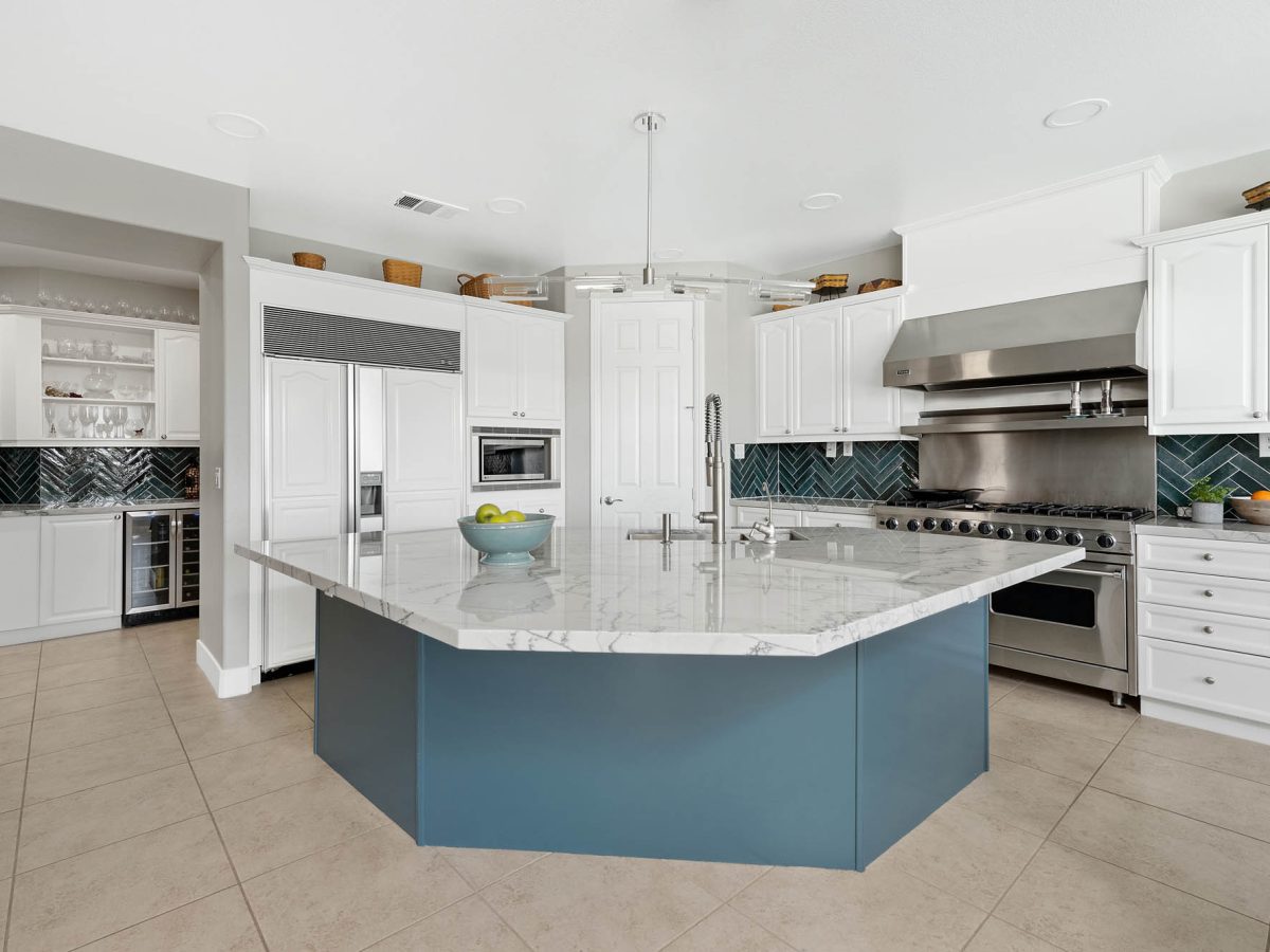 Luxury kitchen with teal painted island, blue-veined quartzite countertops, and herringbone backsplash, Reveal Interior Design Las Vegas