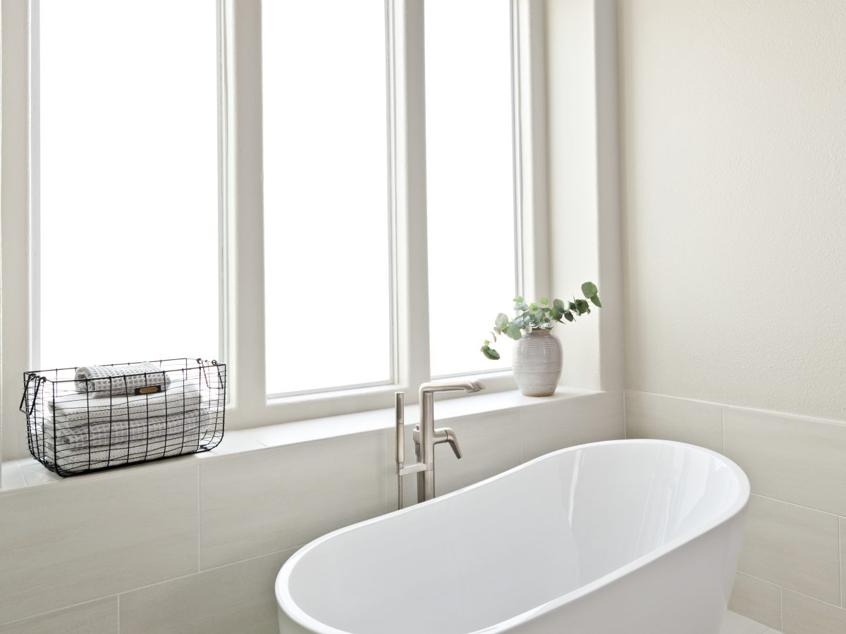 Primary bathroom with freestanding soaking tub, herringbone tile rug, and statement chandelier, Reveal Interior Design Las Vegas