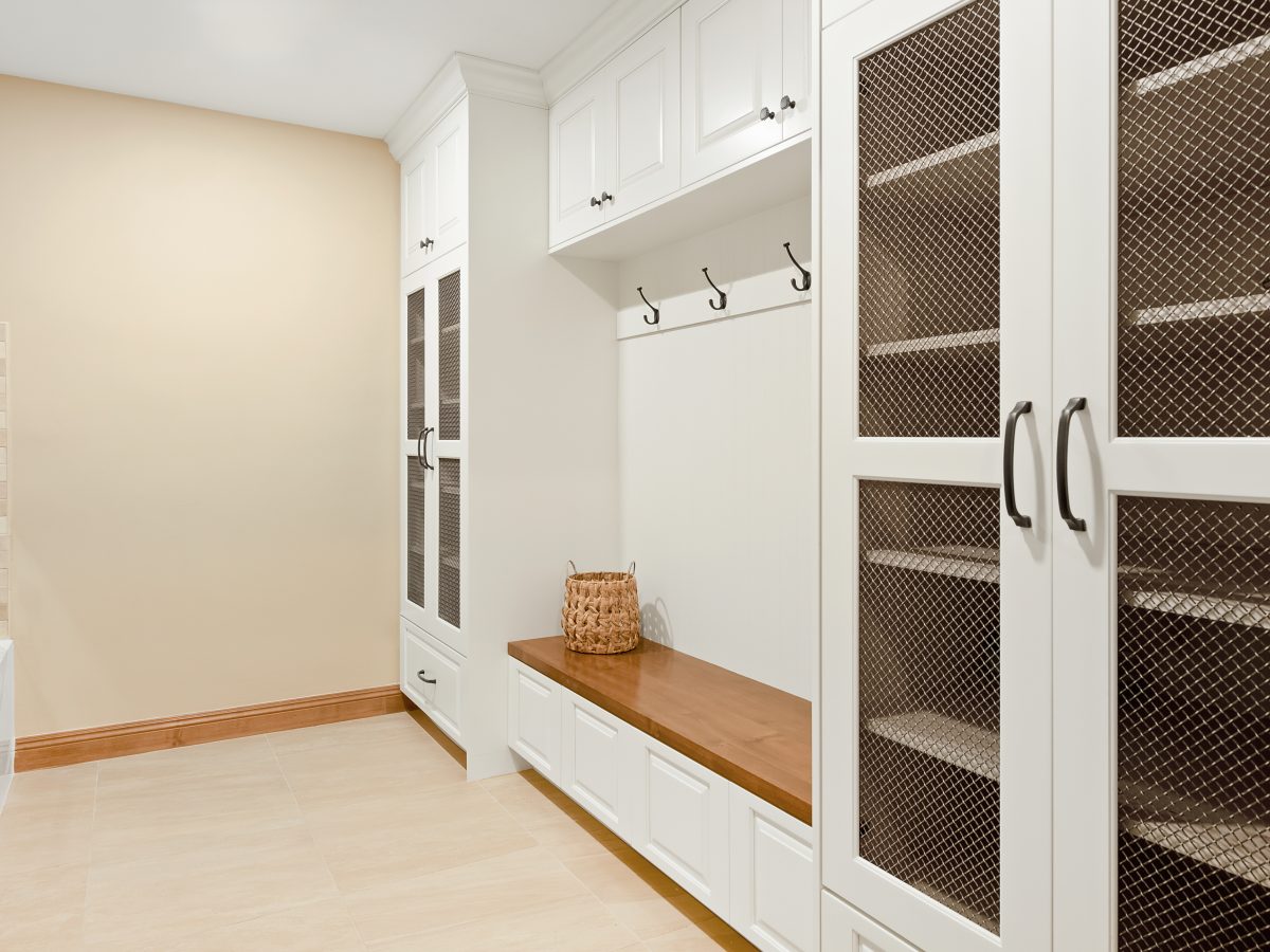 Modern Spanish mudroom with cream cabinetry, bronze mesh cabinet doors, and maple bench seat, Reveal Interior Design Las Vegas
