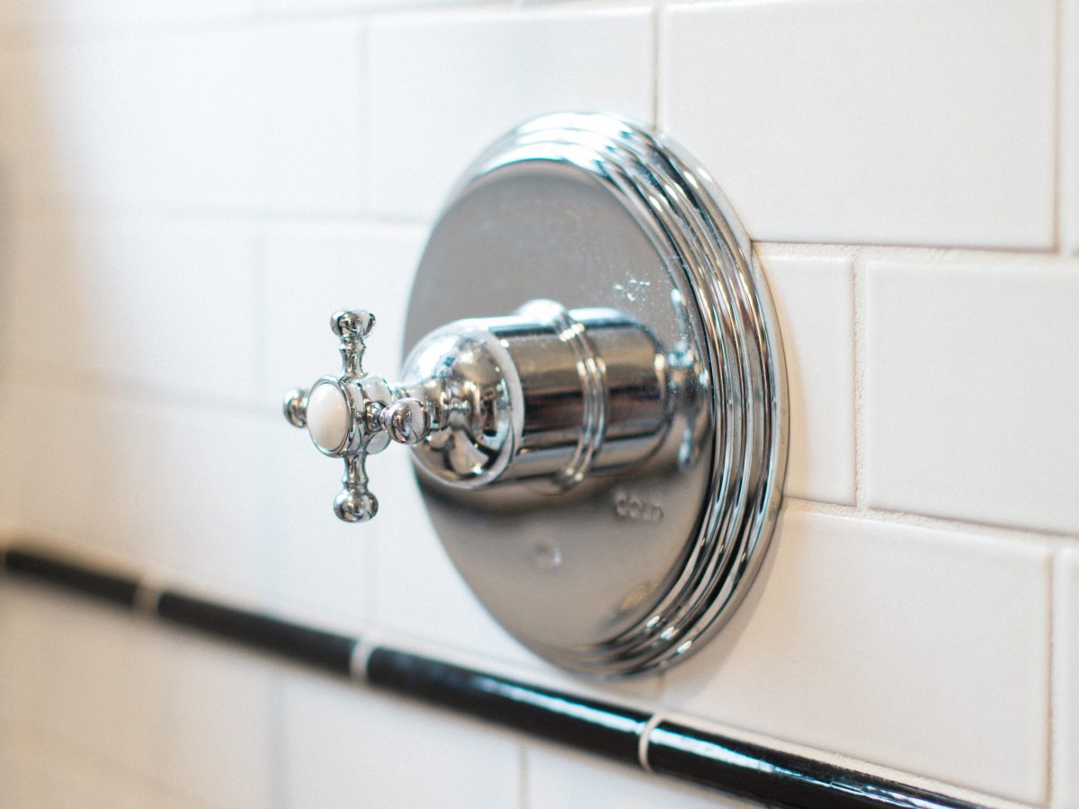 Vintage bathroom shower valve with chrome cross-handle on white subway tile, Reveal Interior Design Las Vegas