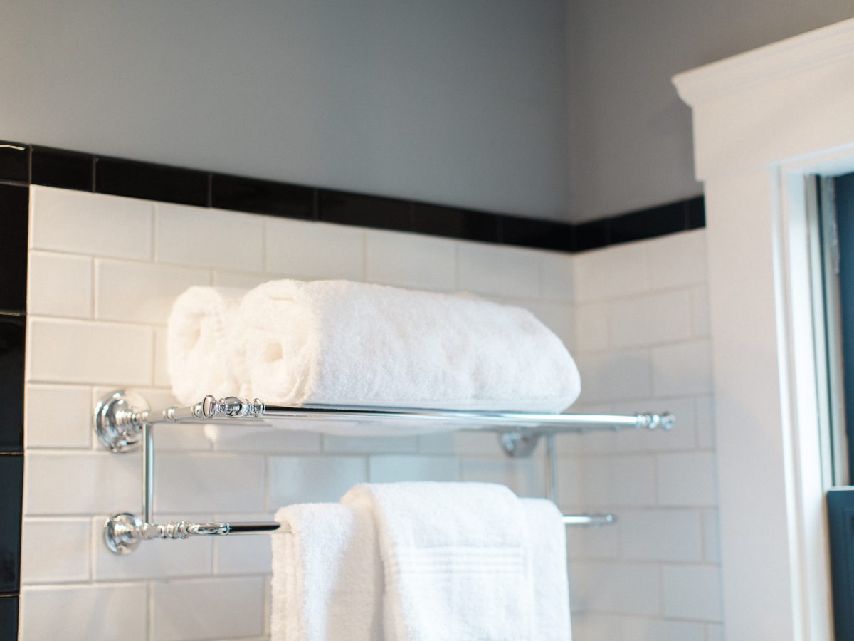 1920s bathroom with white subway tile, black accent trim, and chrome towel rack, Reveal Interior Design Las Vegas