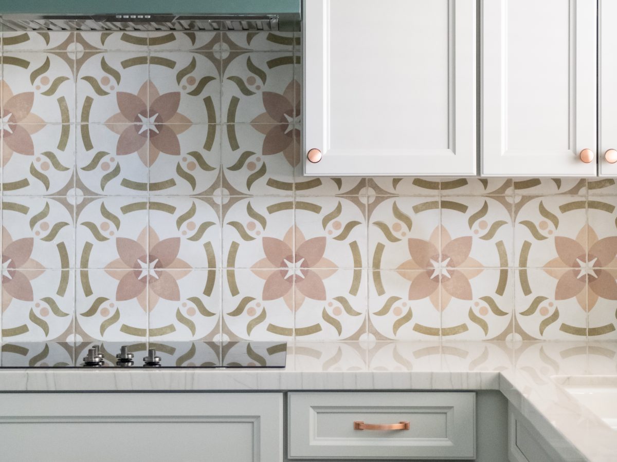 Kitchen with encaustic ceramic tile backsplash, emerald and light beige cabinetry, copper hardware, Reveal Interior Design Las Vegas