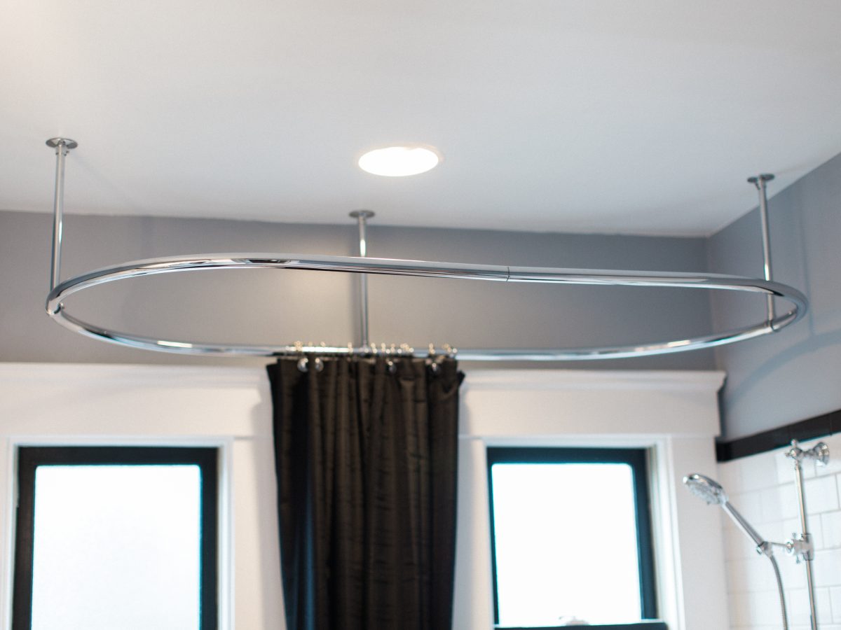 1920s-inspired bathroom with ceiling-mounted oval chrome shower curtain rod and black shower curtain, Reveal Interior Design Las Vegas