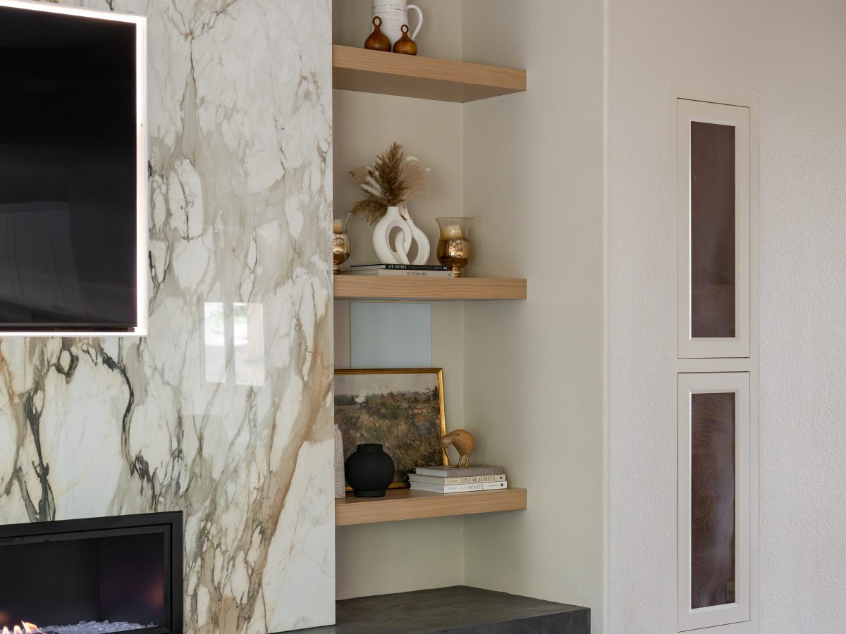Living room with bookmatched porcelain slab fireplace surround, floating oak shelves, and linear fireplace, Reveal Interior Design Las Vegas