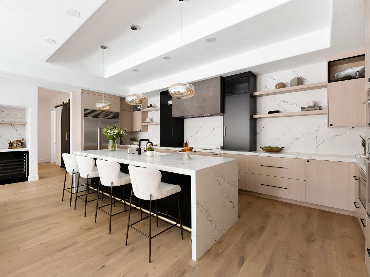 Open-concept kitchen with white-washed oak cabinetry, black quartz countertops, and matte black range hood, Reveal Interior Design Las Vegas