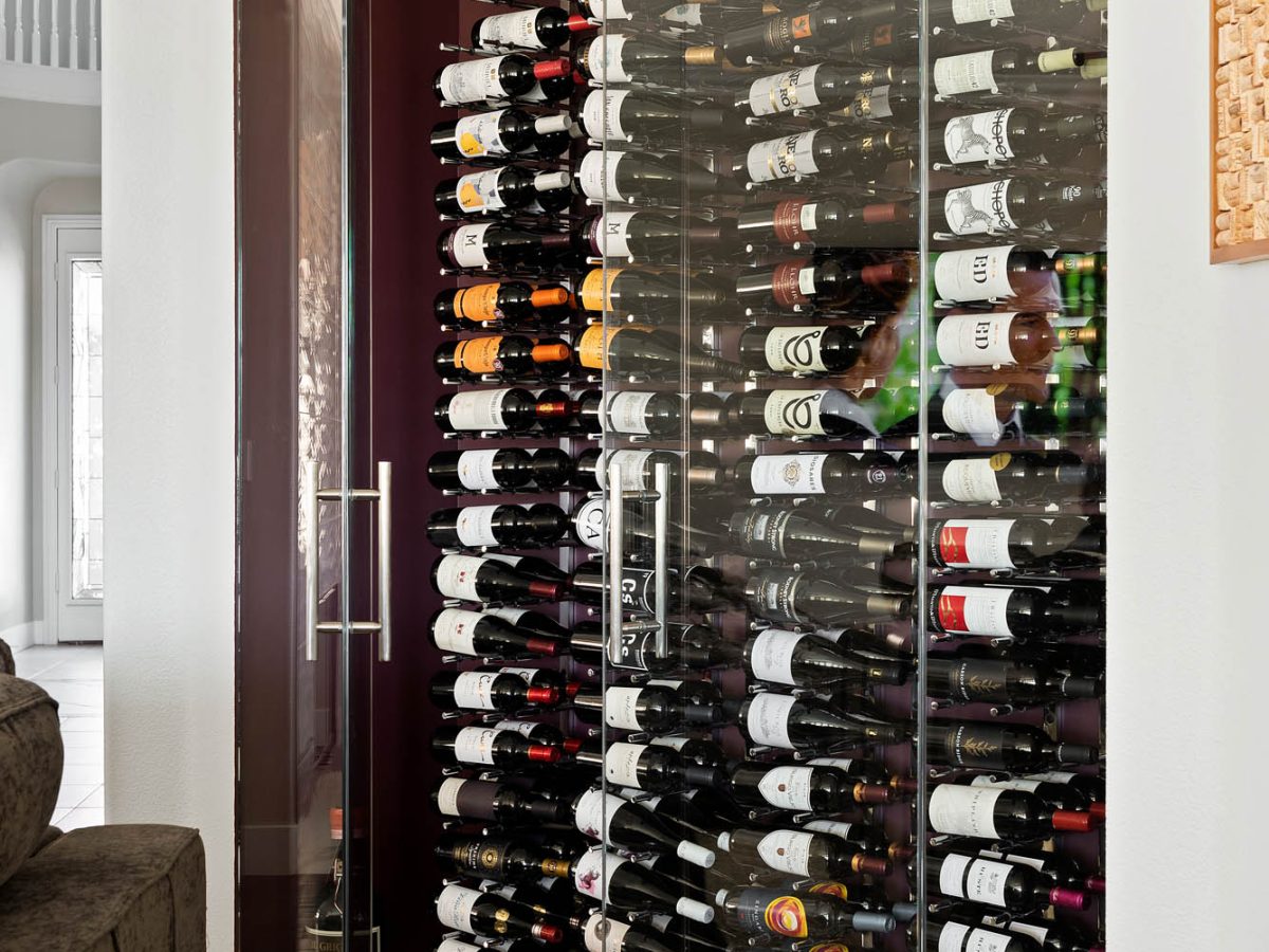 Custom built-in wine storage with glass doors and port wine accent wall, Reveal Interior Design Las Vegas
