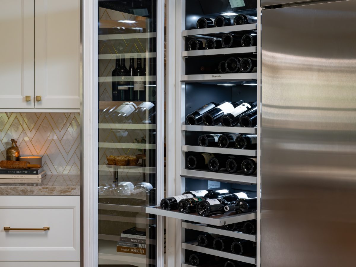 Luxury kitchen wine refrigerator with full-extension shelving and white cabinetry, Reveal Interior Design Las Vegas