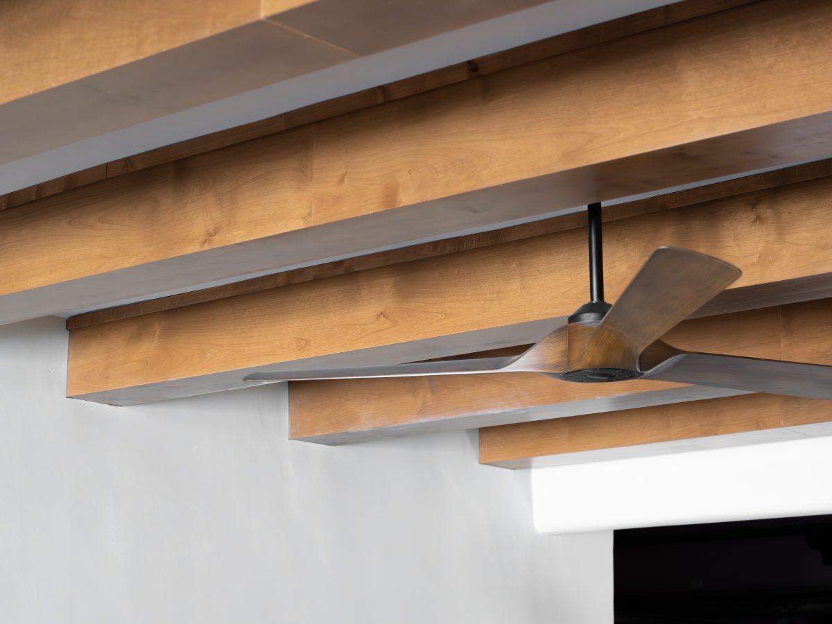 Living room with maple stained ceiling beams and modern three-blade ceiling fan, Reveal Interior Design Las Vegas